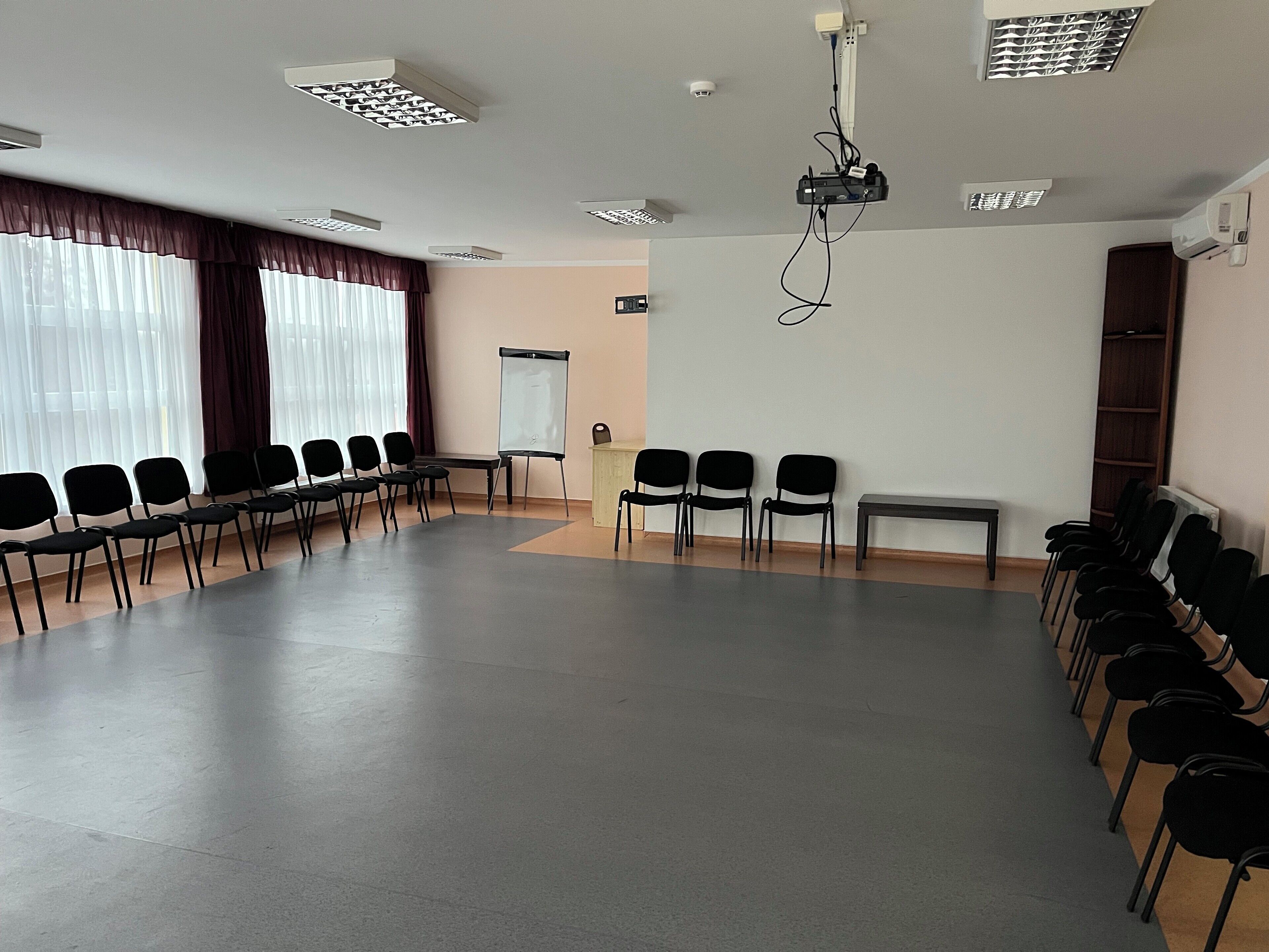 Kokoushuone, jossa on pitkä pöytä, useita rivissä olevia tuoleja, projektori ja valkotaulu.