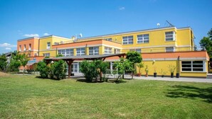 Un bâtiment jaune doté d’un espace extérieur abrité et d’un terrain herbeux devant.