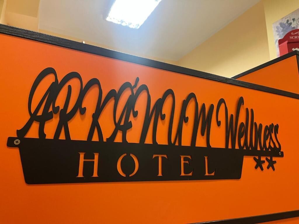 A sign with the text "ARKANSAS ROOM WELLNESS HOTEL" on an orange background.