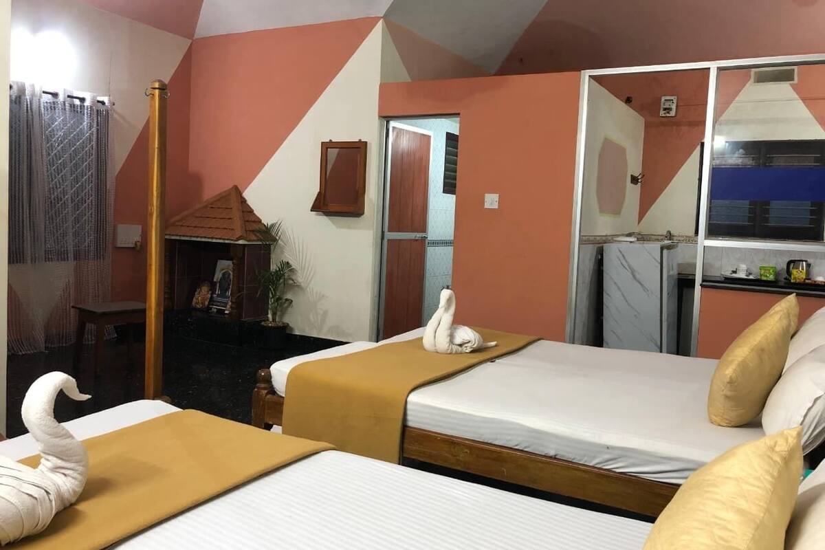 A hotel room with two beds, a mirror, a small table, and a window.