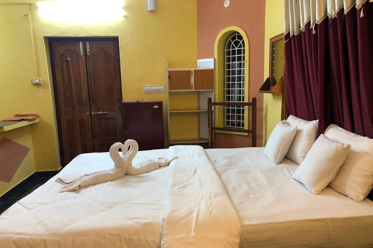 A hotel room with a bed, a wardrobe, a desk, and a window with curtains.