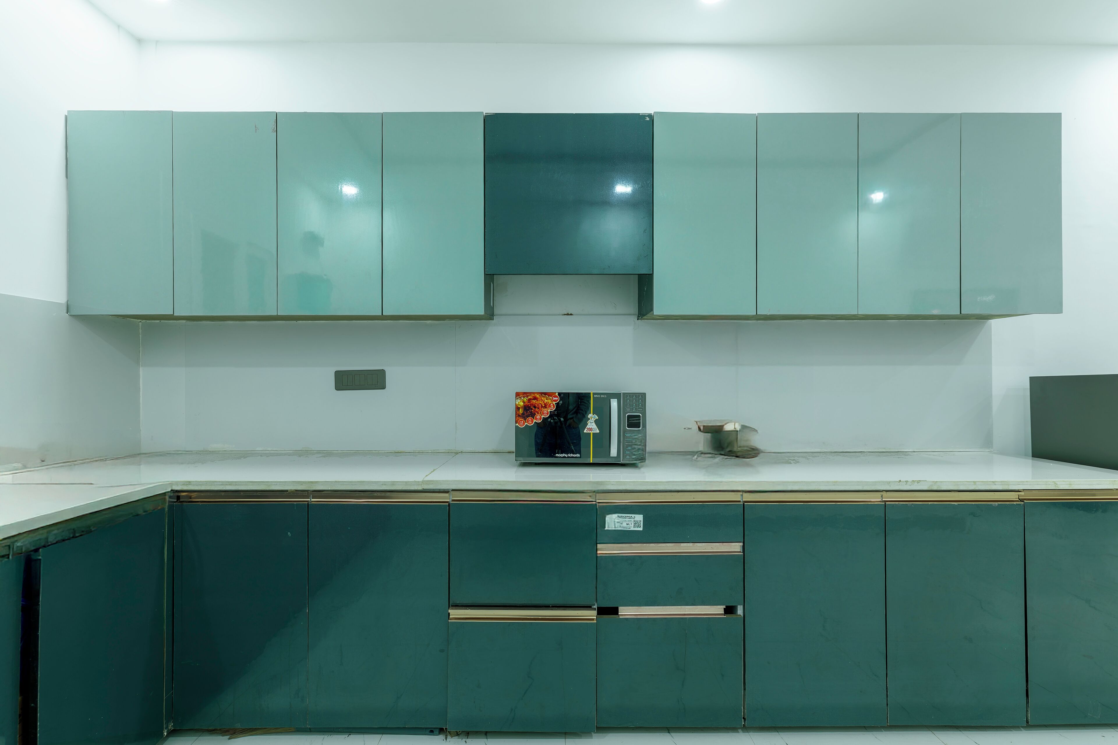 Una cocina con armarios verde mar, un microondas y un lavabo.