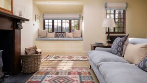 A cozy living room with a built-in bench, a fireplace, a sofa, and a patterned rug. - The Queen's Hut - Idyllic Log Cabin, originally built for Queen Mary (Aboyne)