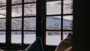A window with a view of a snowy landscape, including trees and a hill. - The Queen's Hut - Idyllic Log Cabin, originally built for Queen Mary (Aboyne)