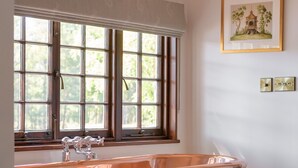 A bathroom with a copper bathtub, large windows, and a framed picture on the wall. - The Queen's Hut - Idyllic Log Cabin, originally built for Queen Mary (Aboyne)