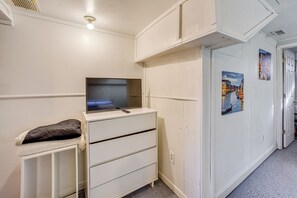 A white room with a TV on a dresser, a small table with a pillow, and two paintings on the wall. - < 1 Mi to Downtown! Old North End Studio w/ Patio (Colorado Springs)