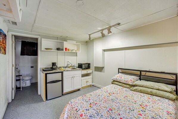Une chambre compacte comprenant un lit, une petite kitchenette et une salle de bain.