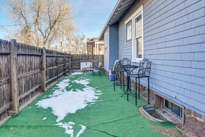 Un jardin avec une pelouse artificielle, une clôture en bois et du mobilier d’extérieur.