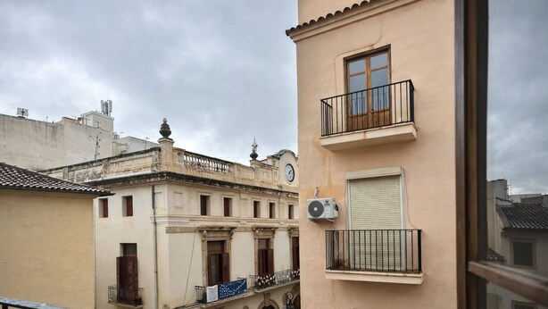 Ein Gebäude mit Balkon, einer Uhr und einer Klimaanlage.