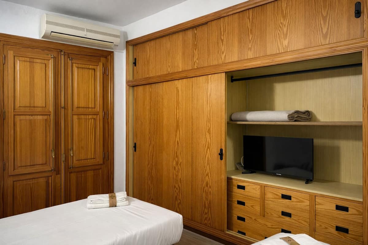 Une chambre à coucher avec un lit, une armoire en bois et un téléviseur posé sur un meuble.