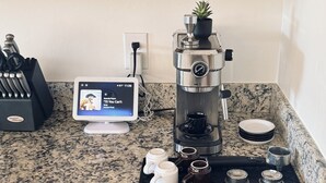 Cozinha com armários de madeira, cafeteira, tablet e porta-facas.