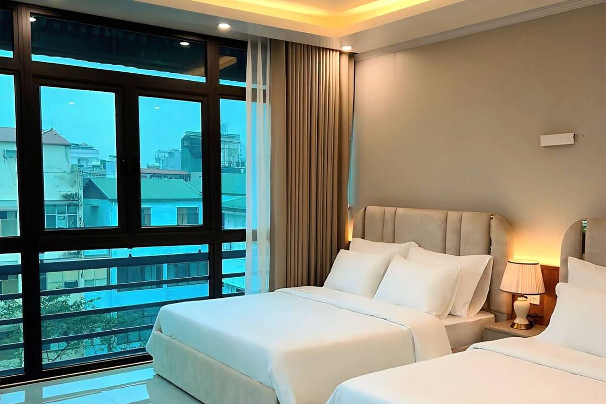 A hotel room with two beds, a large window with a city view, and a modern design.