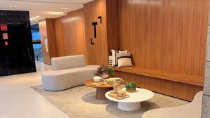 Un vestíbulo moderno con un sofá, una mesa redonda de centro y una pared decorativa de madera.