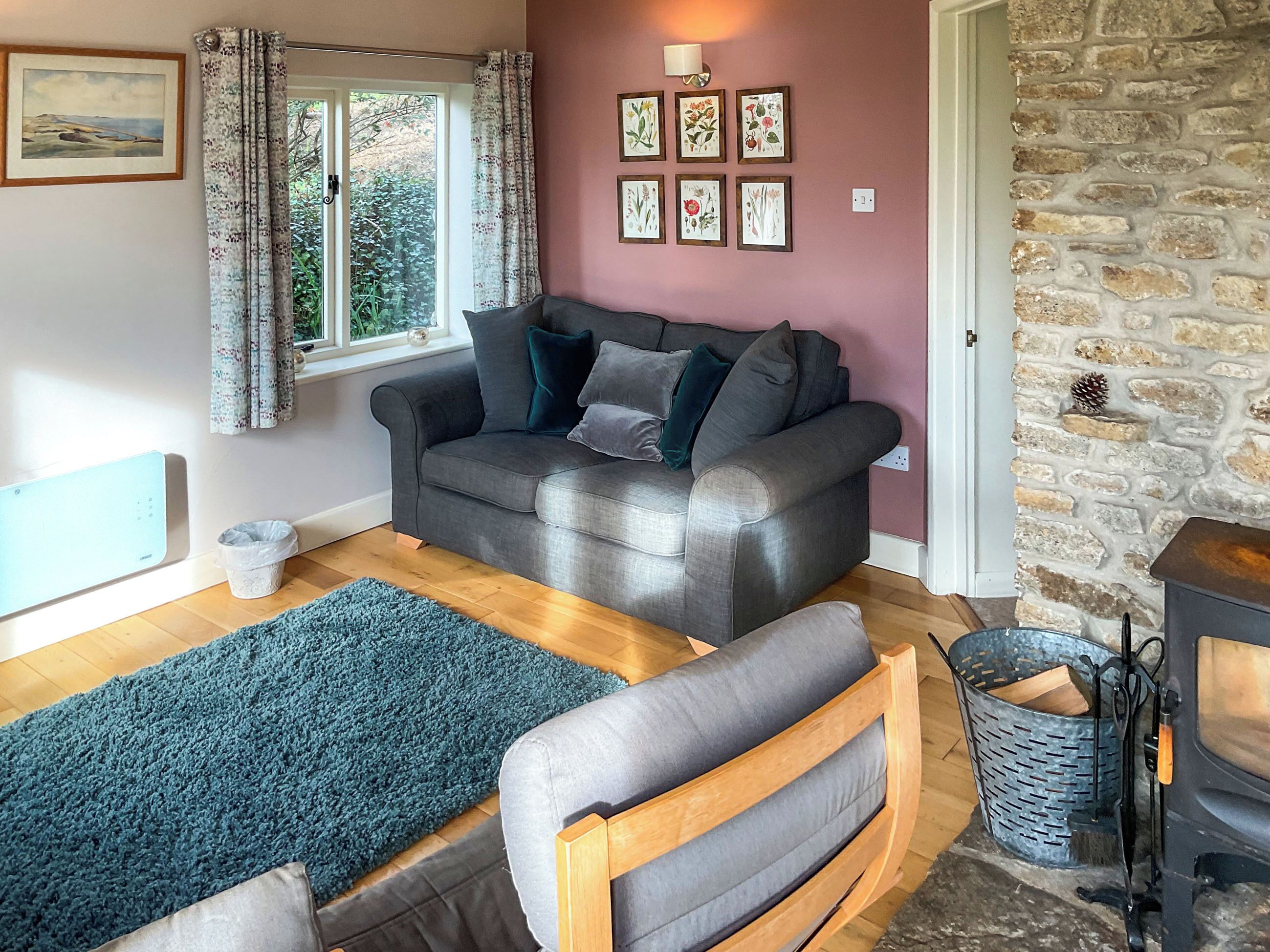 A cozy living room with a sofa, a rug, a fireplace, and framed botanical prints on the wall.