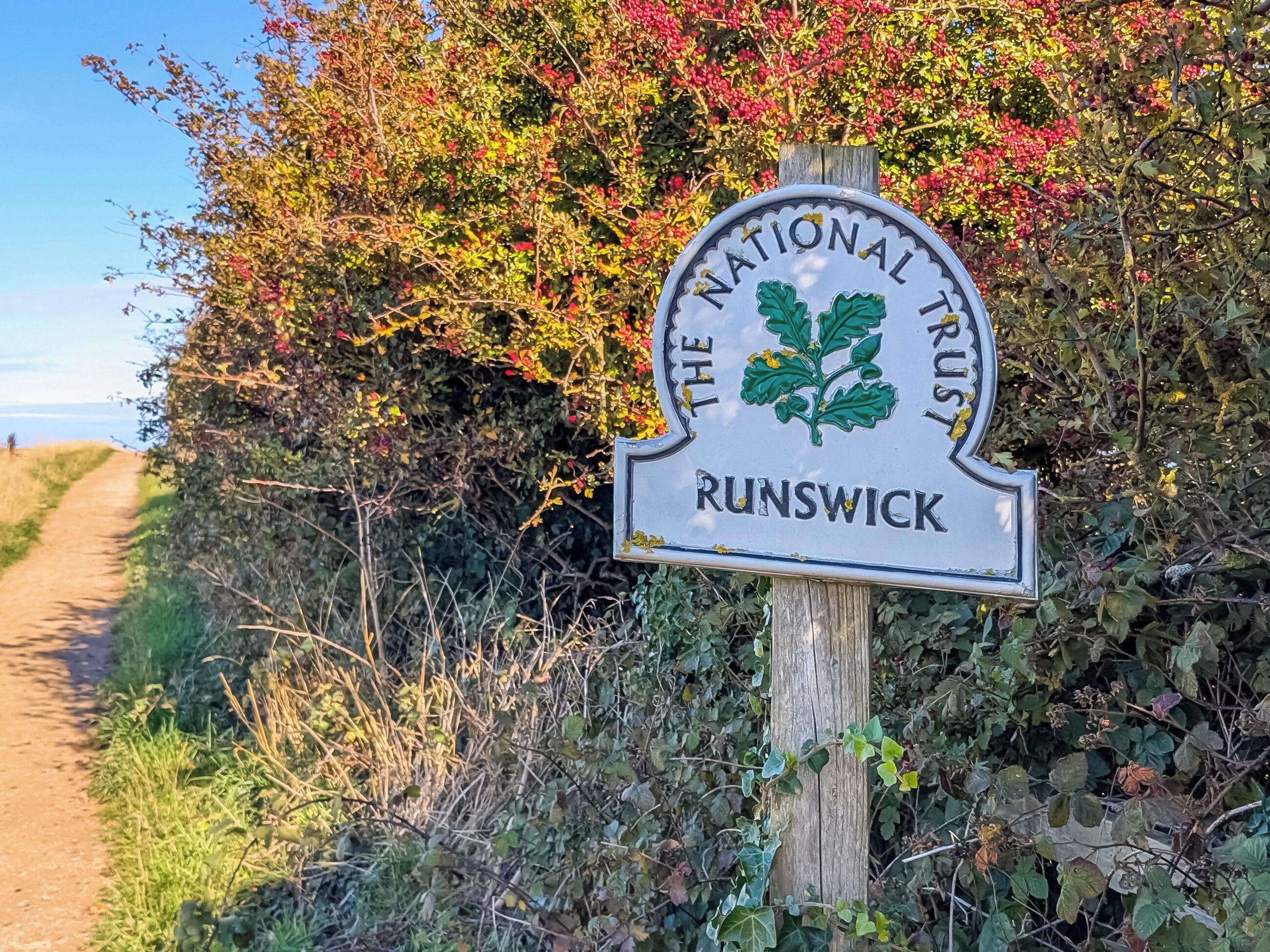 Ein Schild des National Trust in Runswick, mit einem Weg, der in die Ferne führt.