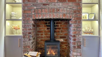 A brick fireplace with a wood-burning stove, flanked by shelves with decorative items.