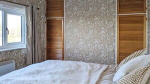 Una camera da letto con un letto, tende, una finestra e un termosifone.