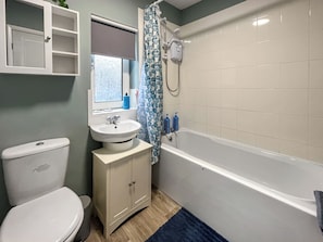A bathroom with a toilet, sink, cabinet, shower, and a blue bath mat. - 3 bedroom accommodation in Chapel St. Leonards (Chapel St. Leonards)