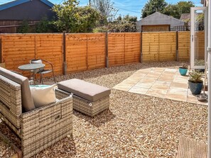A patio area with a wicker sofa, a small table, and a potted plant. - 3 bedroom accommodation in Chapel St. Leonards (Chapel St. Leonards)