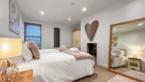 Een slaapkamer met een groot bed, nachtkastjes, een spiegel en een radiator.