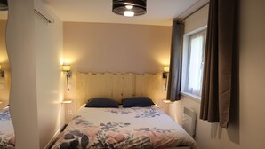 Een hotelkamer met een groot bed, een houten hoofdeinde, twee bedlampen en een raam met gordijnen.
