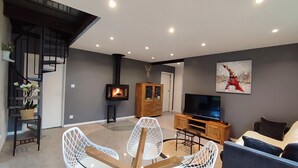 Een moderne woonkamer met een open haard, een televisie en een trap.