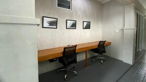 A conference room with a long wooden table, two black office chairs, and three framed photographs on the wall. - Villa Kulat (Pecatu)