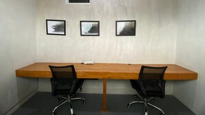 A conference room with a long wooden table, two black office chairs, and three framed pictures on the wall. - Villa Kulat (Pecatu)