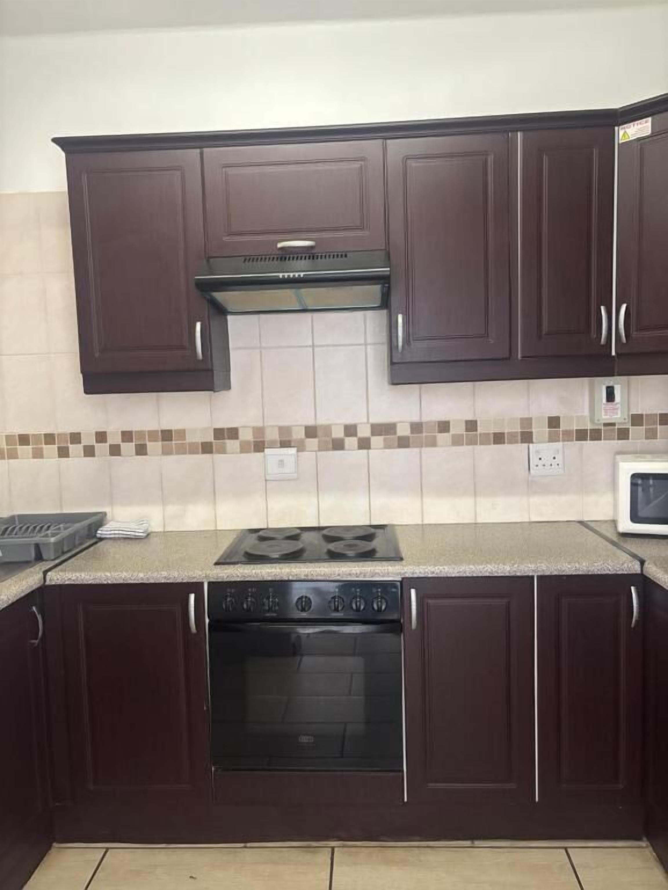 A kitchen with dark brown cabinets, a gas stove, an oven, and a microwave.