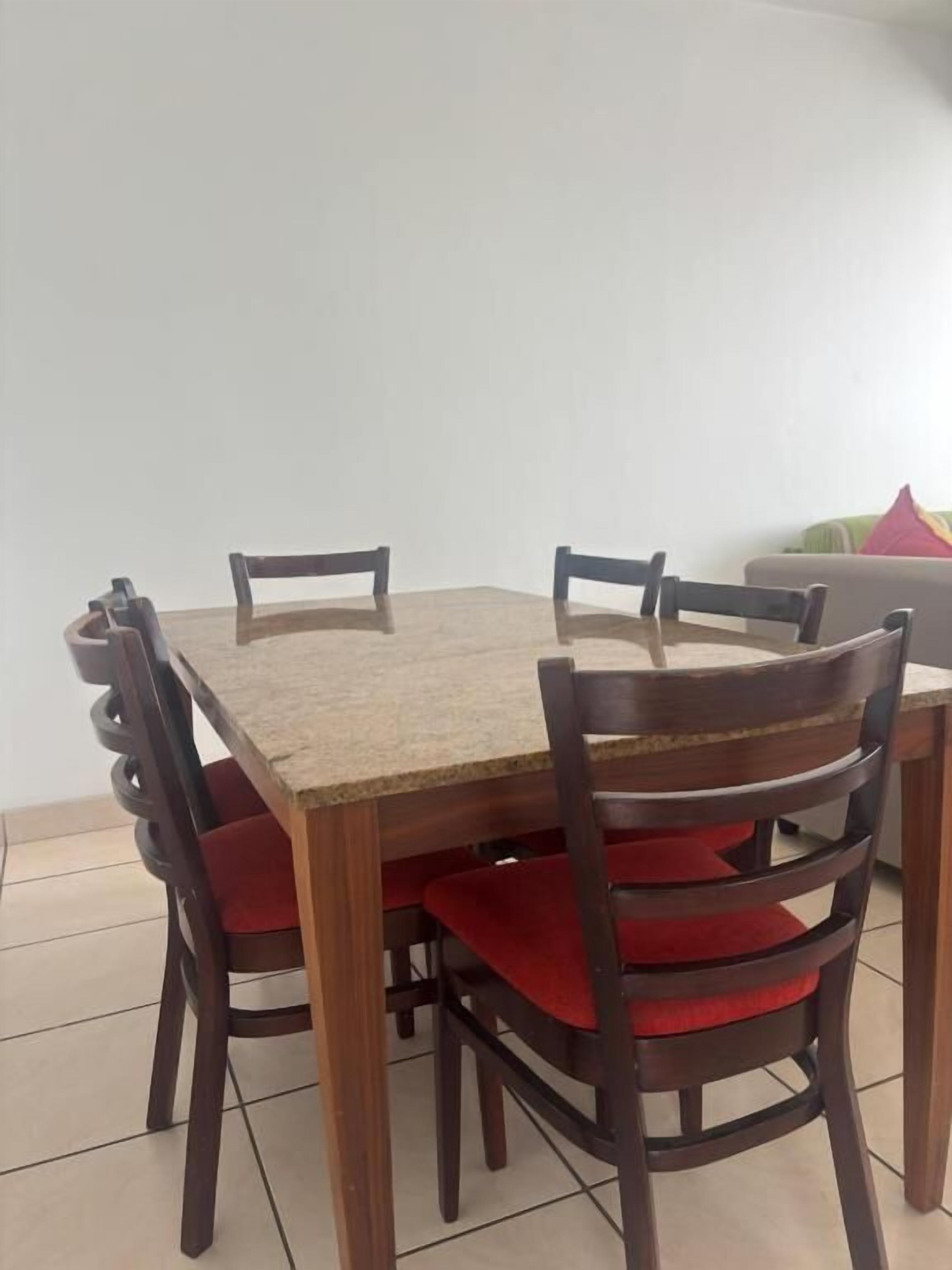 Une table à manger avec six chaises, chacune dotée d’un coussin rouge.