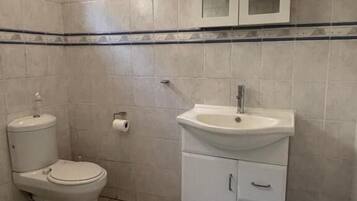 A small bathroom with a toilet, sink, and cabinet.