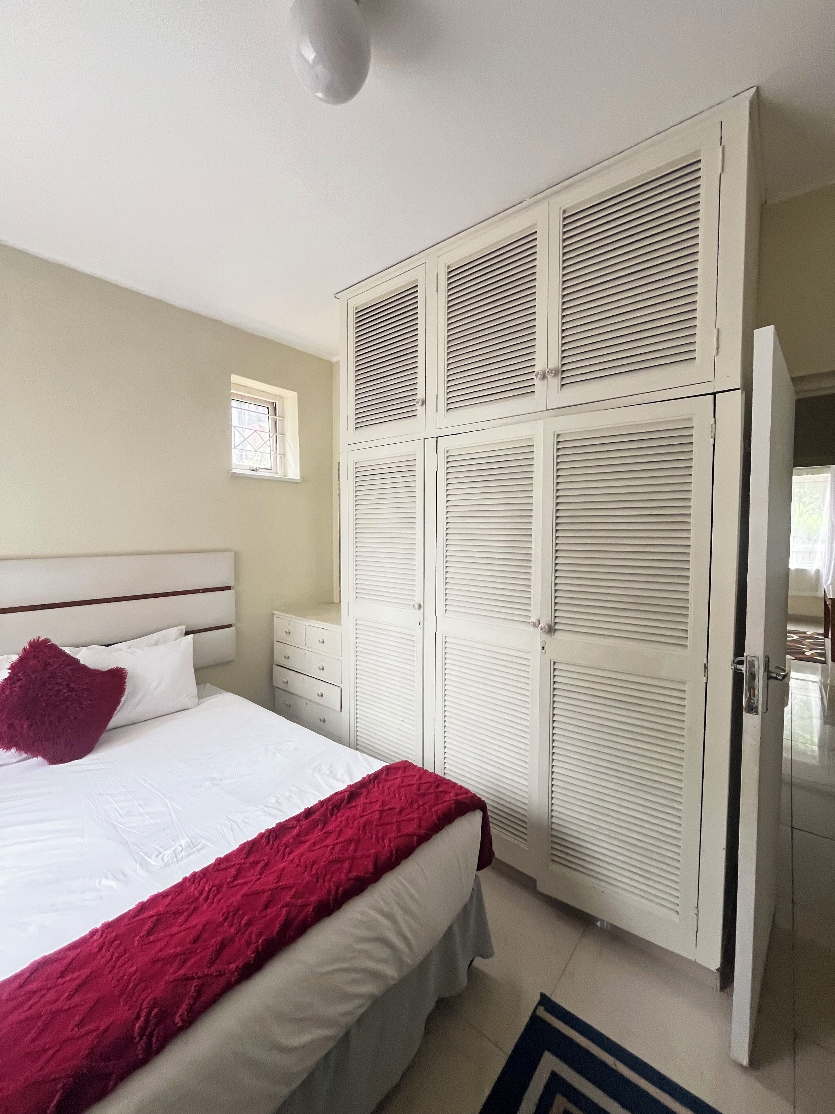 Un dormitorio con cama, armario y mesita de noche.