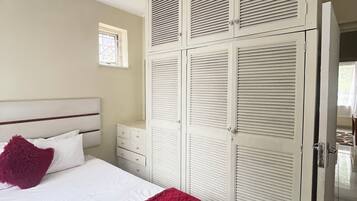 Un dormitorio con cama, armario y mesita de noche.