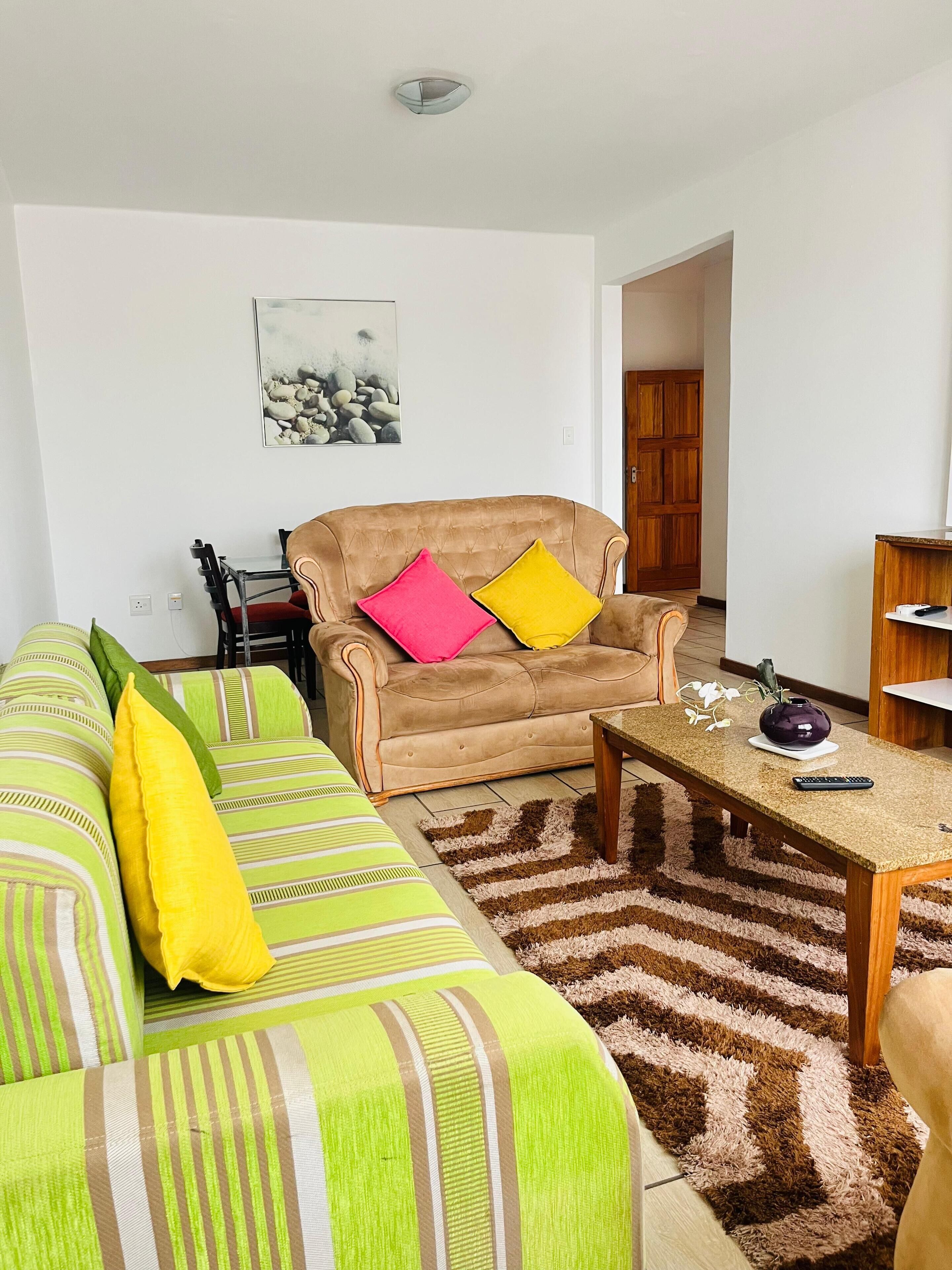 A living room with a sofa, a coffee table, and a painting on the wall.