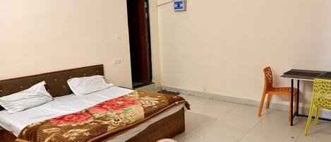 A bedroom with a bed, a small table, and a chair.