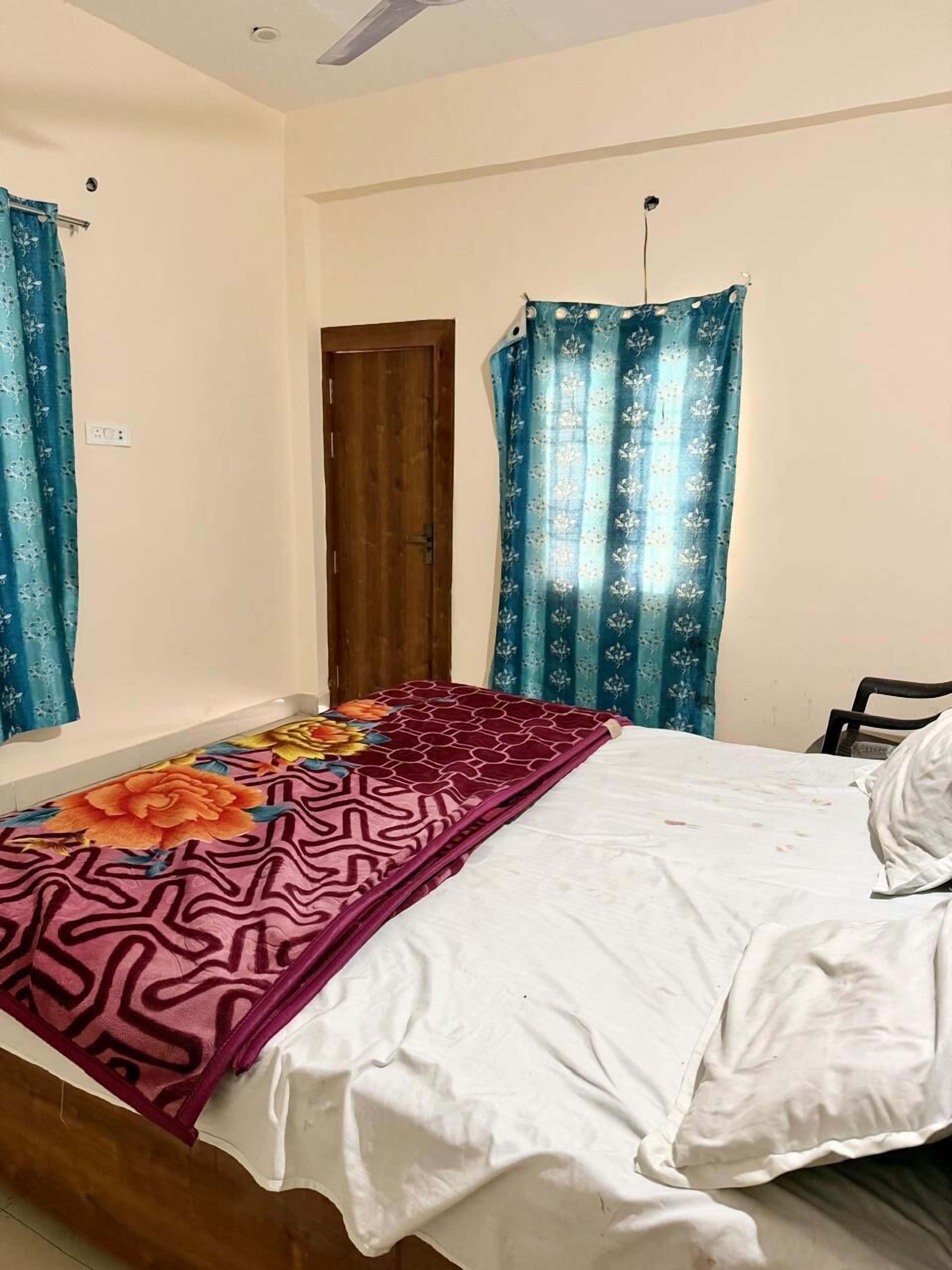 Ein Schlafzimmer mit einem Bett, einer Holztür und blauen Vorhängen.