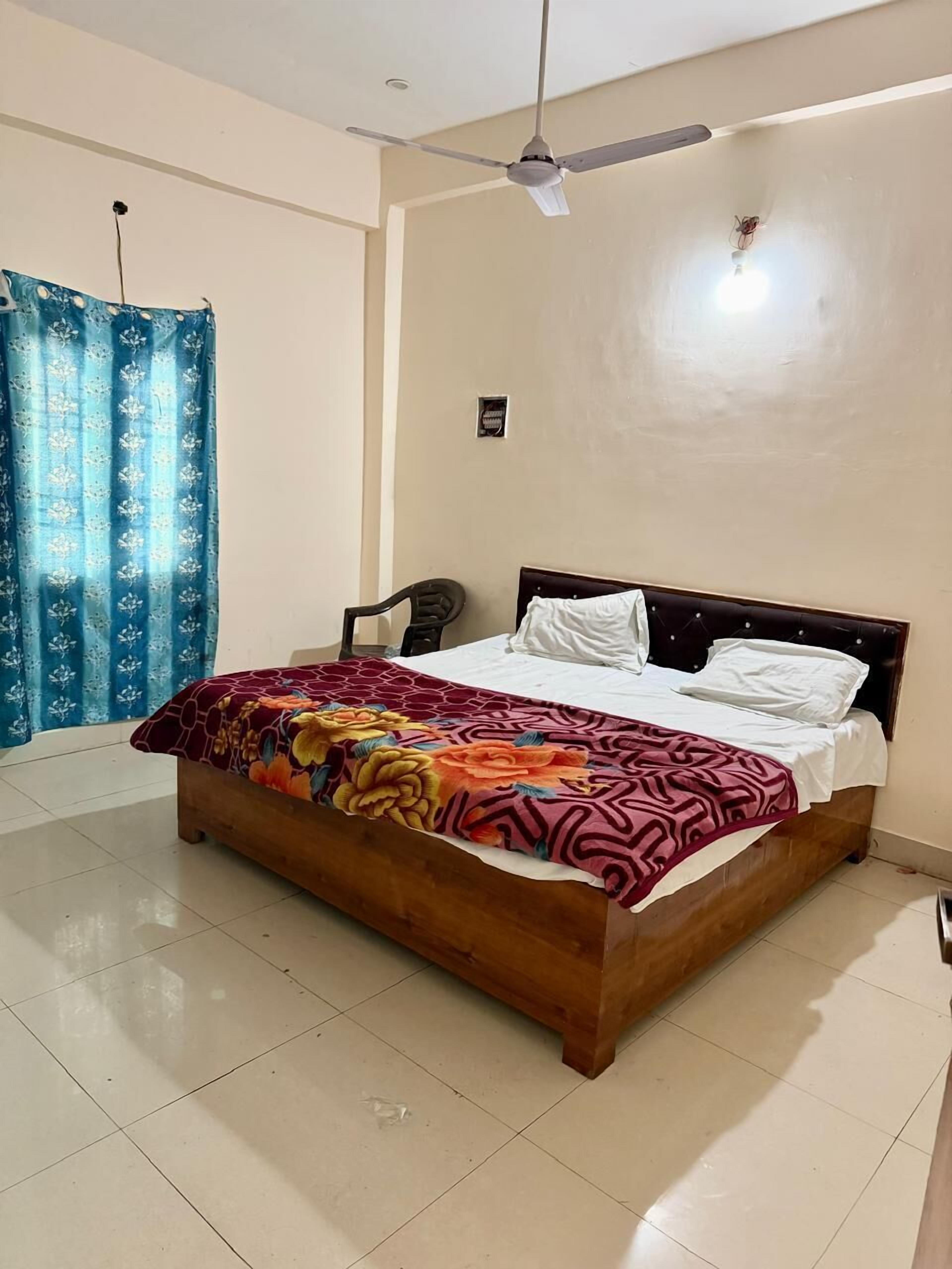A bedroom with a bed, a ceiling fan, a window with curtains, and a tiled floor.