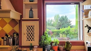 A kitchen with a window view of a garden, a sink, and various kitchen utensils. - Villa Near Avignon With Separate Suites (Robion)