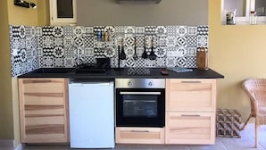 A compact kitchen with a patterned backsplash, a built-in oven, and a refrigerator. - Villa Near Avignon With Separate Suites (Robion)