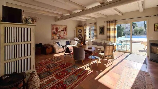 A spacious living room with a large window, a sofa set, a patterned rug, and a decorative cabinet. - Villa Near Avignon With Separate Suites (Robion)