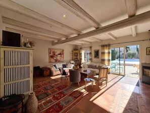 A spacious living room with a large window, a sofa set, a patterned rug, and a decorative cabinet. - Villa Near Avignon With Separate Suites (Robion)