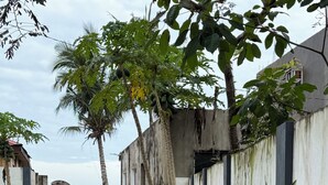 A paved pathway leading to a building with a concrete exterior and a metal fence. - Beautiful 2-bedroom apartment with AC, beach front and huge parking lot (Opol)