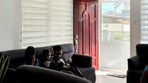A modern living room with a ceiling fan, a red door, and a view of the outside. - Beautiful 2-bedroom apartment with AC, beach front and huge parking lot (Opol)