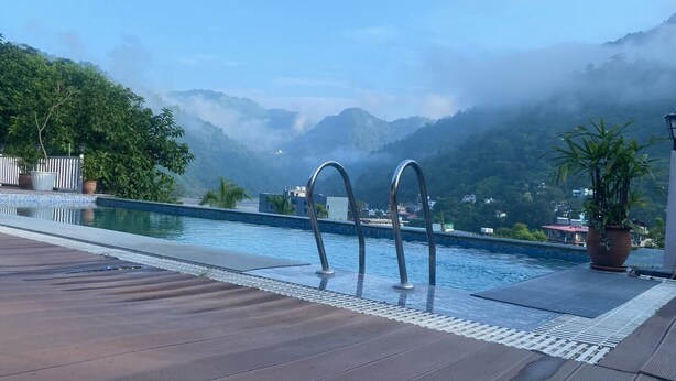 A pool area with a view of mist-covered mountains, a wooden deck, and a metal railing.