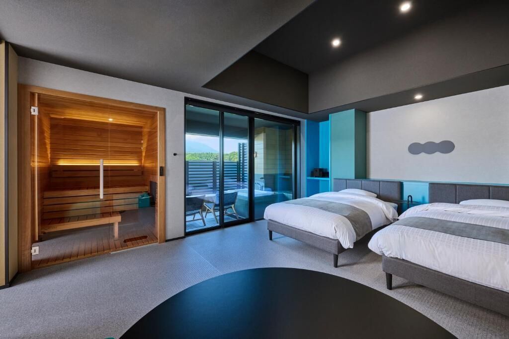 Una habitación de hotel moderna con una cama grande, una sauna de madera y una puerta corrediza de cristal a un balcón.