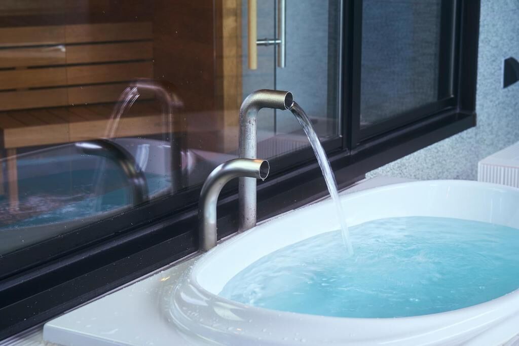 A modern bathroom with a white bathtub and a faucet.