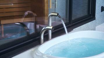 A modern bathroom with a white bathtub and a faucet.