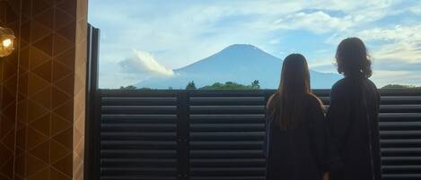 Deux personnes se tiennent près d’une fenêtre, d’où l’on peut admirer un paysage de montagne.