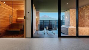 Une chambre d’hôtel moderne dotée d’une porte-fenêtre coulissante donnant sur un balcon avec vue sur les montagnes.