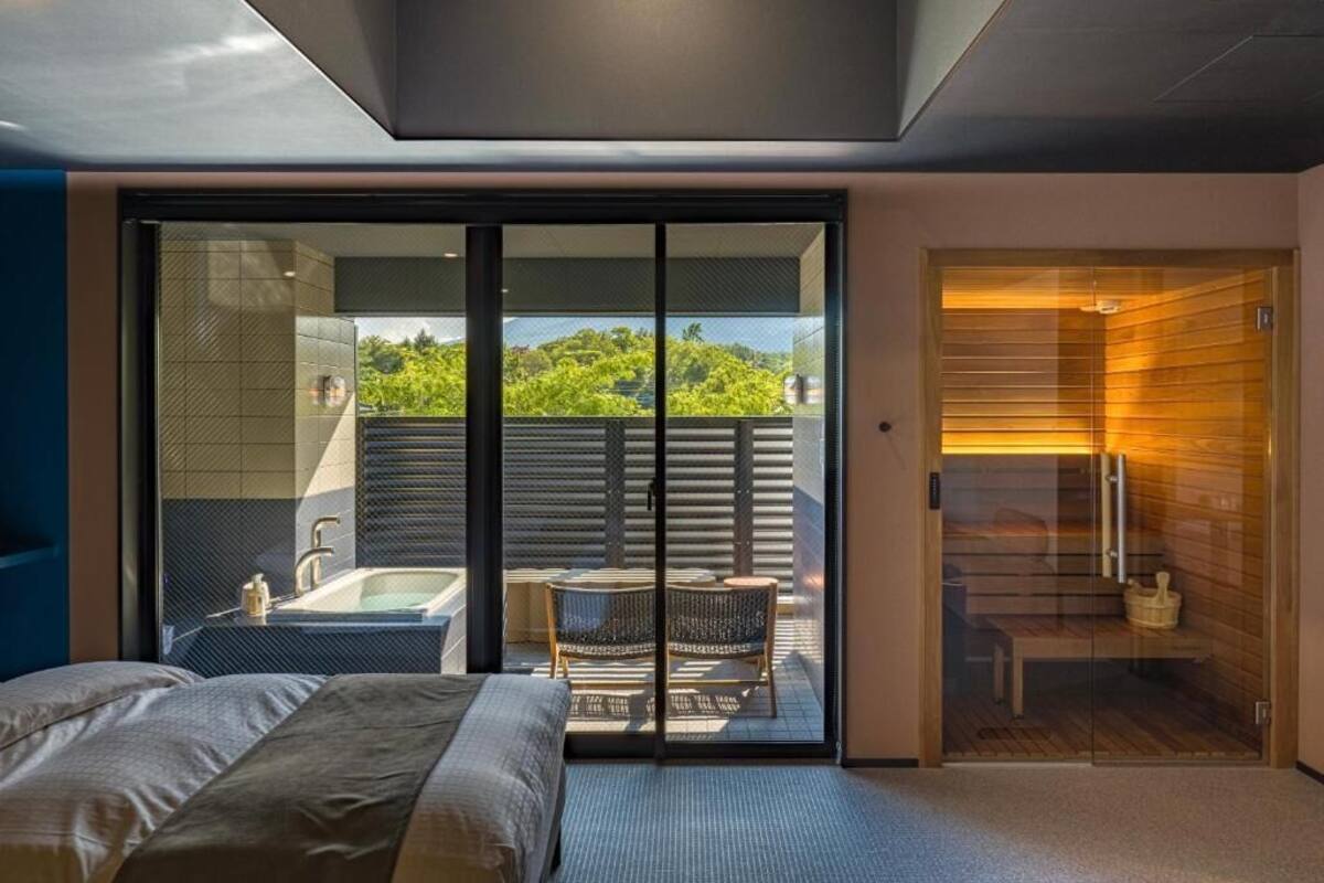 Un dormitorio moderno con una cama grande, un cristal que da a un balcón con bañera y zona de estar.